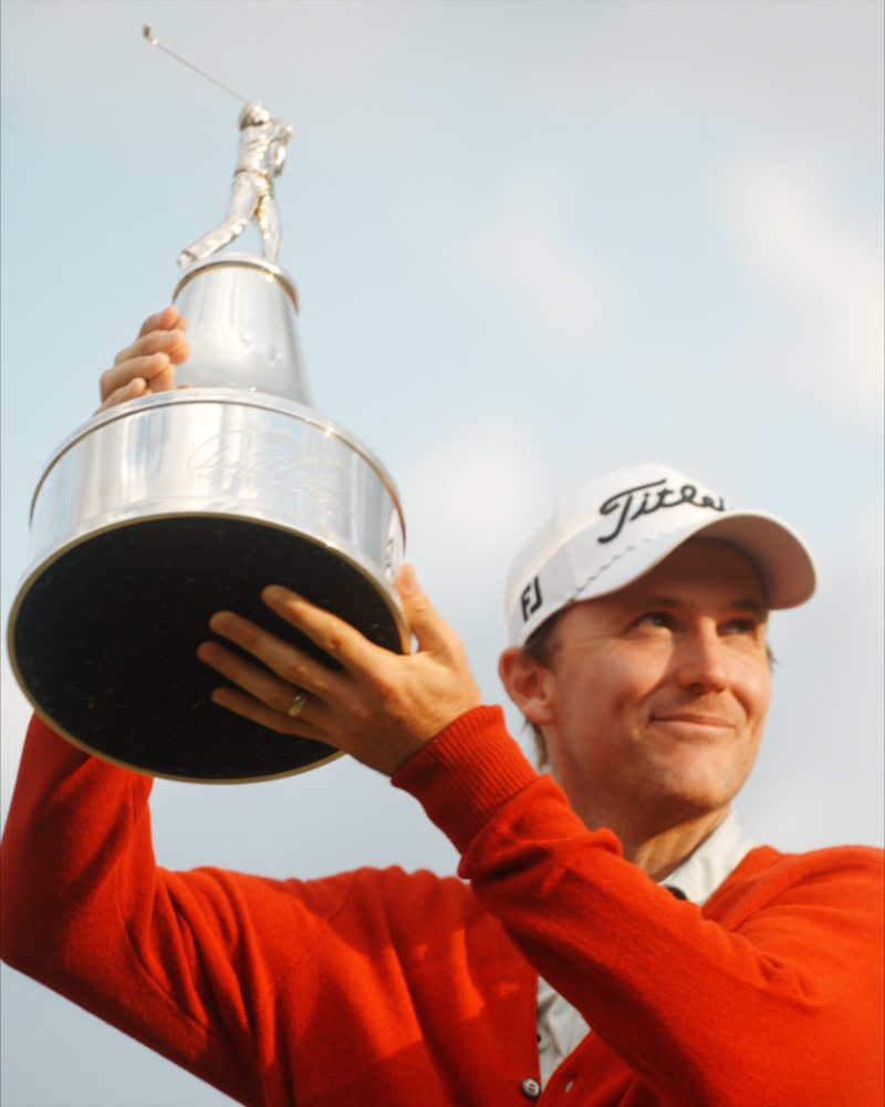 Golfer lifting trophy against blue sky