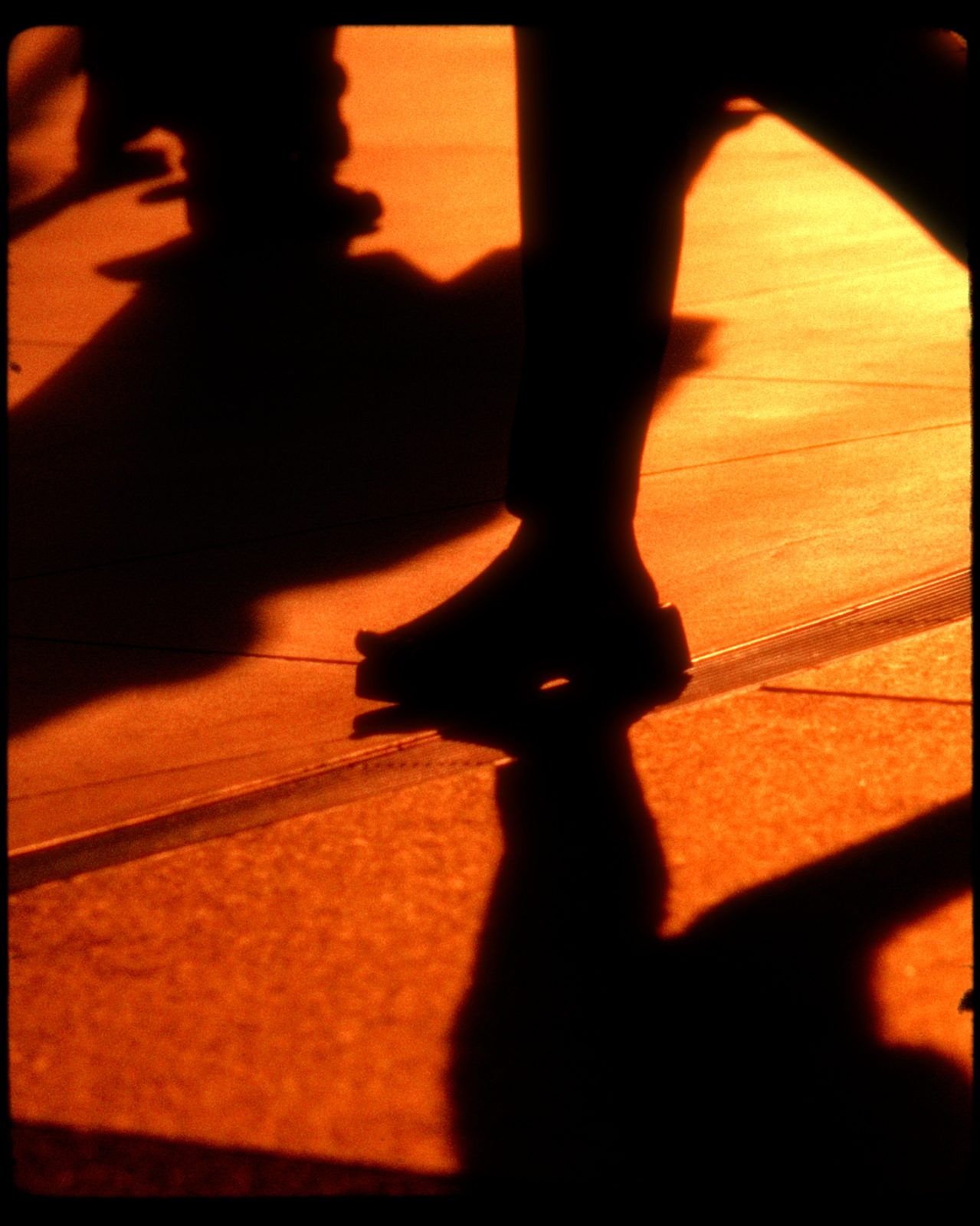 Silhouetted feet walking in amber light