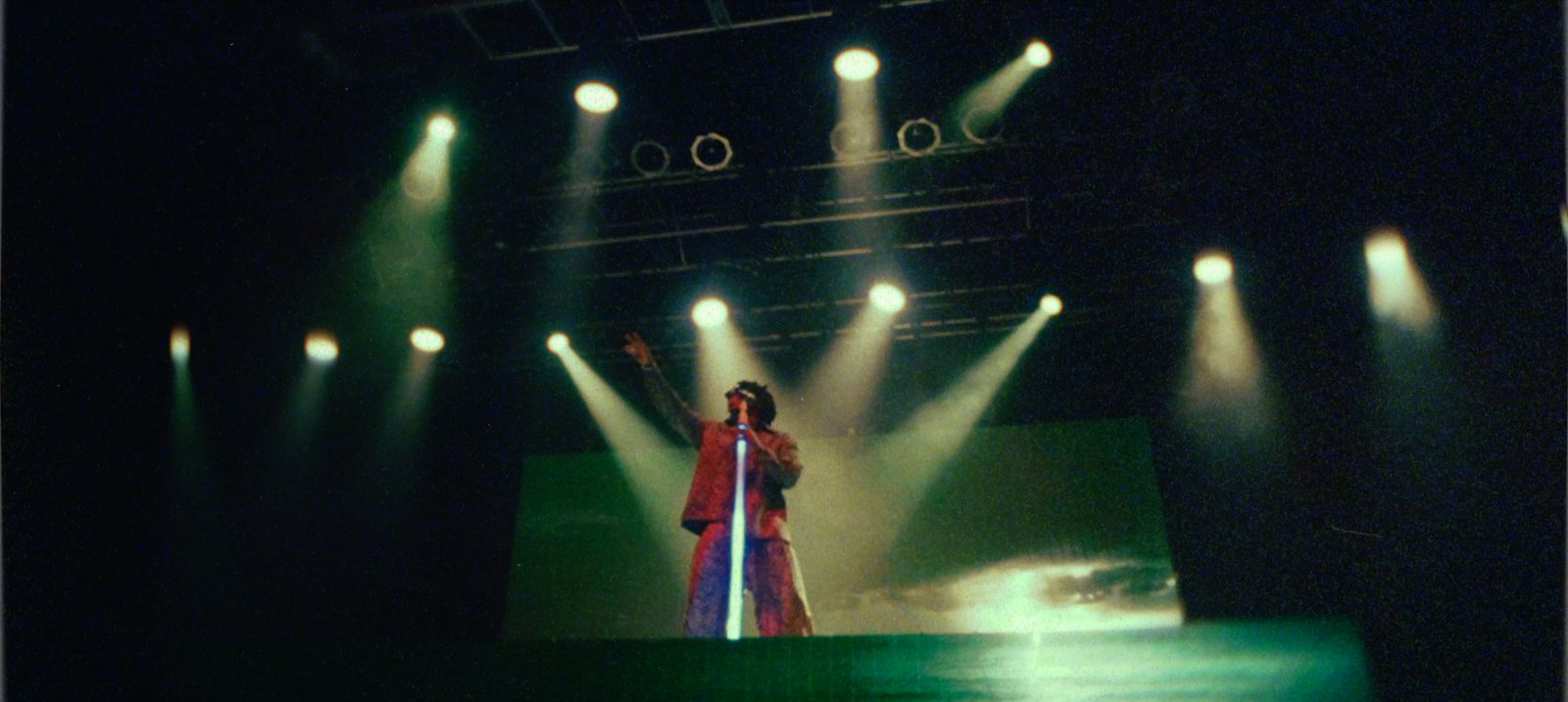 Solo performer under dramatic green spotlights