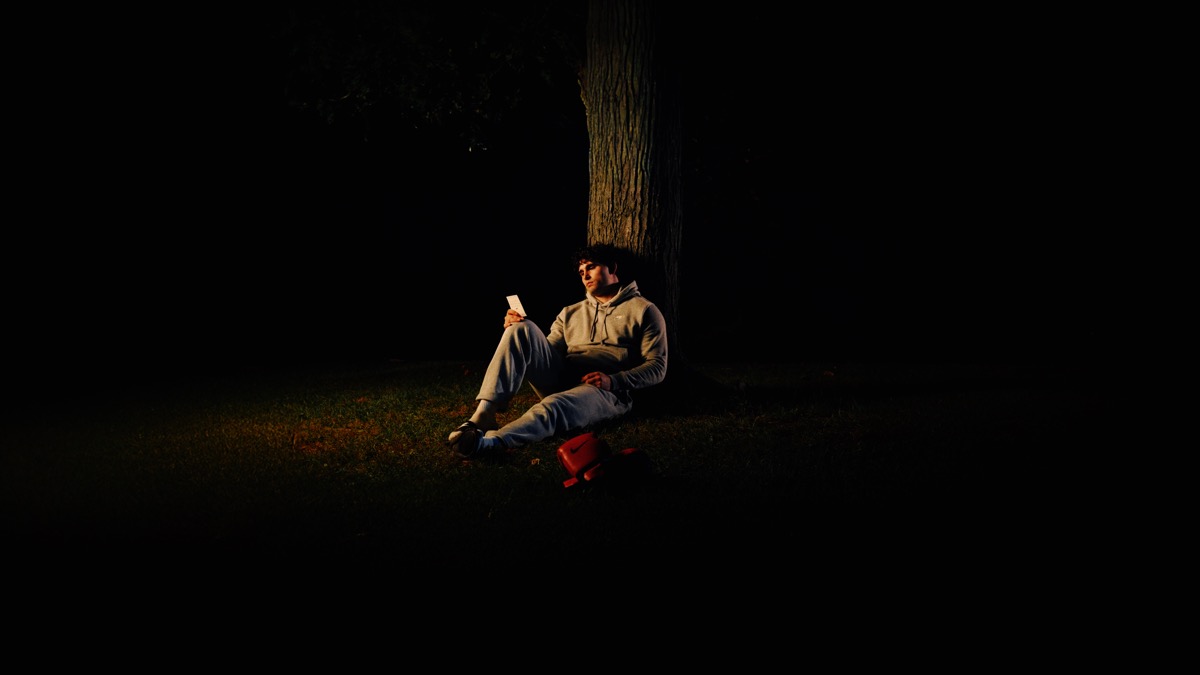 Figure sitting against tree in cinematic night
