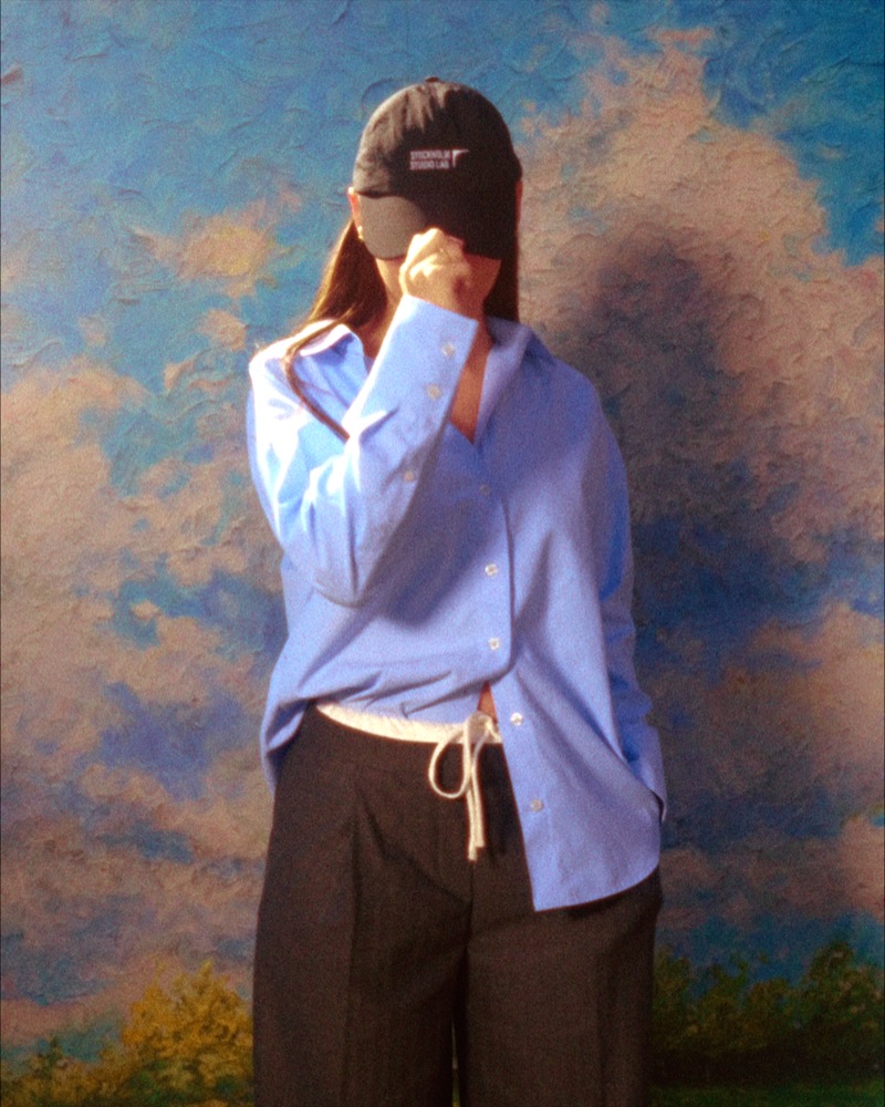 Woman in blue against painted sky backdrop